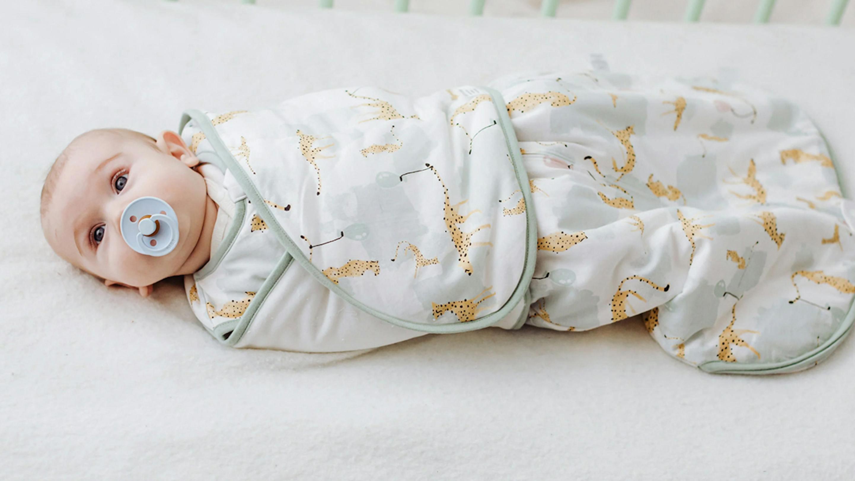 Newborn baby sleeping soundly in Nest Designs' swaddle sleep bag